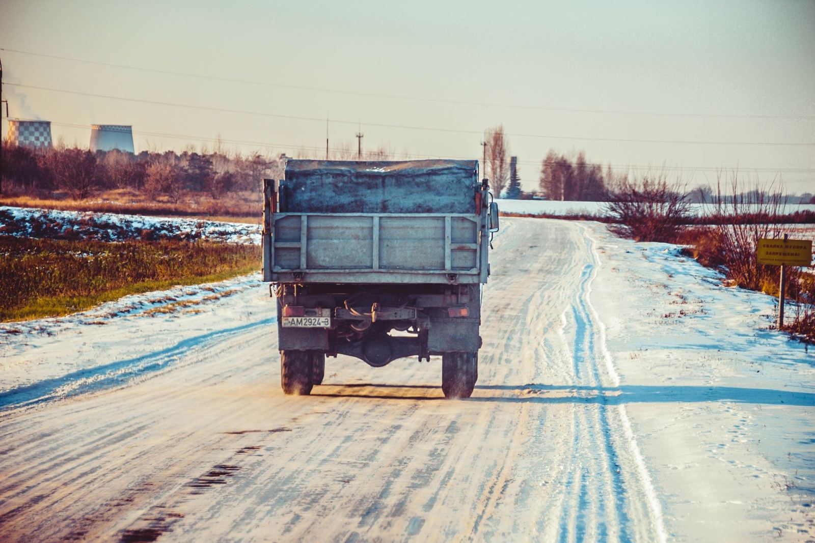 Dump truck driving down a snow-covered rural road in winter